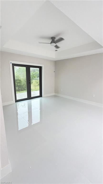 Unfurnished room featuring french doors, a ceiling fan, and a raised ceiling