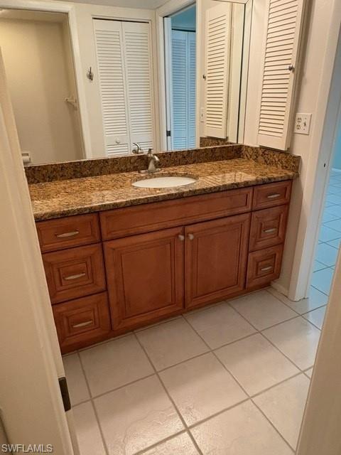 Bathroom featuring light tile patterned flooring, vanity, and a closet