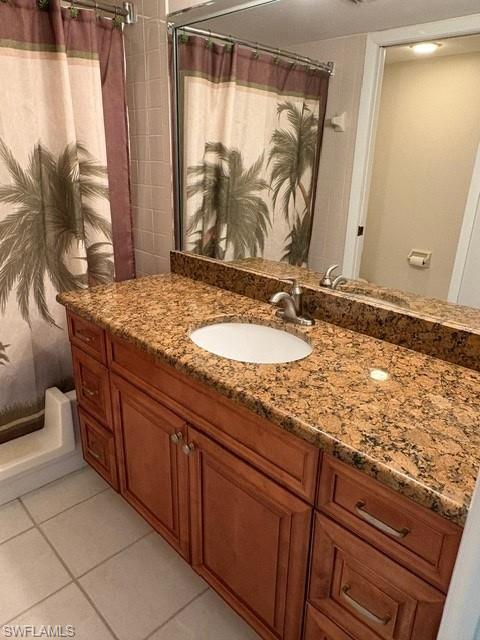 Full bathroom featuring vanity, curtained shower, and light tile patterned flooring