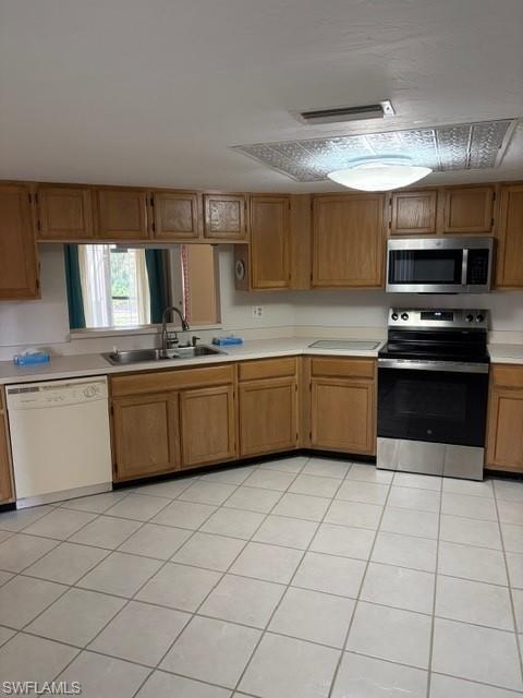 Kitchen featuring stainless steel appliances, light countertops, light tile patterned flooring, and wood finish cabinets