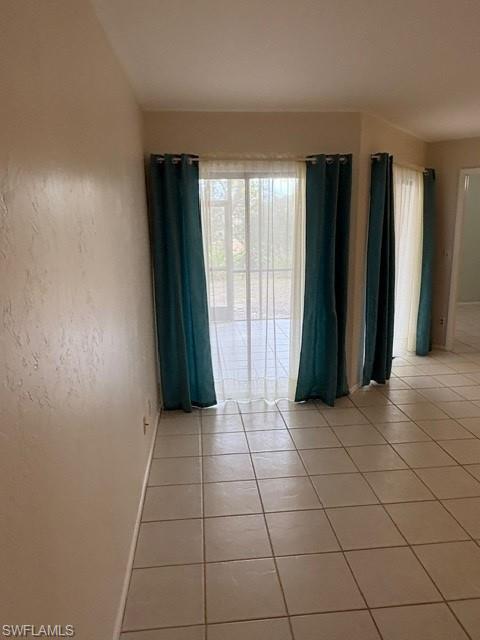 Empty room featuring light tile patterned floors and healthy amount of natural light