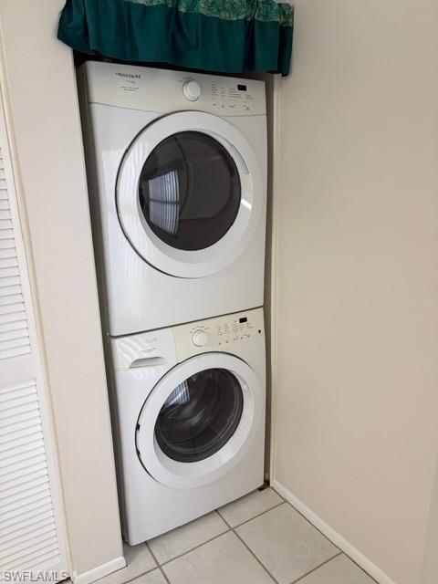 Laundry area with stacked washer / drying machine and light tile patterned floors
