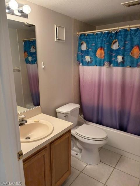 Bathroom with vanity, shower / bath combo with shower curtain, light tile patterned floors, and a textured ceiling