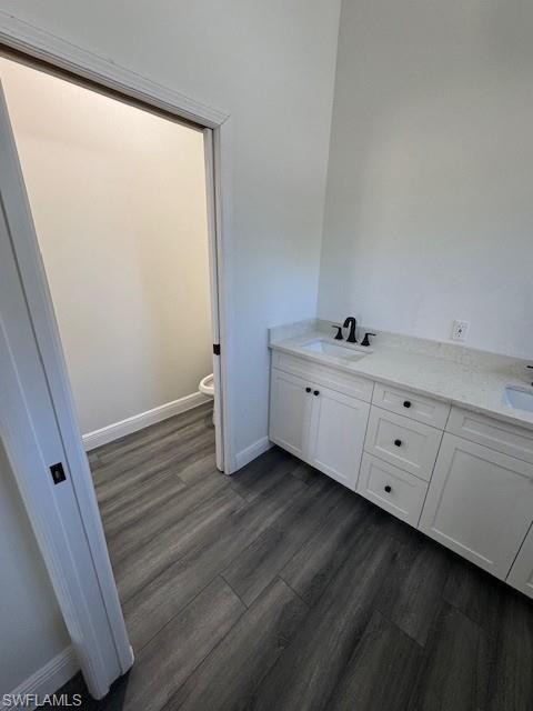 Full bath featuring double vanity and dark wood finished floors