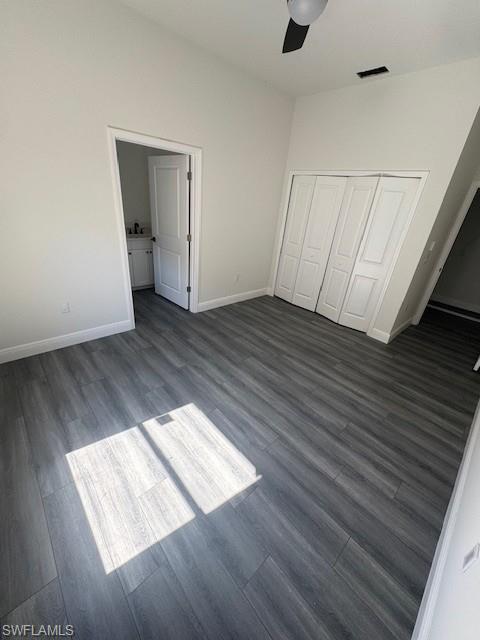 Unfurnished bedroom with wood finished floors, a closet, a ceiling fan, and connected bathroom