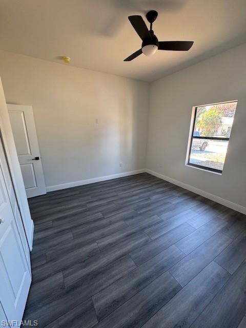 Empty room featuring ceiling fan and dark wood-style floors