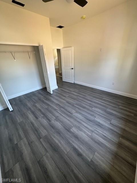 Unfurnished bedroom with a closet, a ceiling fan, and dark wood-style floors