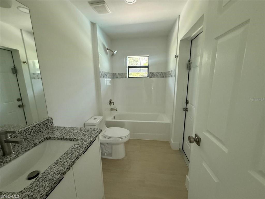 Full bath with vanity, shower / washtub combination, and light wood-type flooring