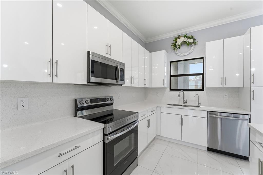 Kitchen with stainless steel appliances, tasteful backsplash, white cabinets, light marble finish floors, and crown molding