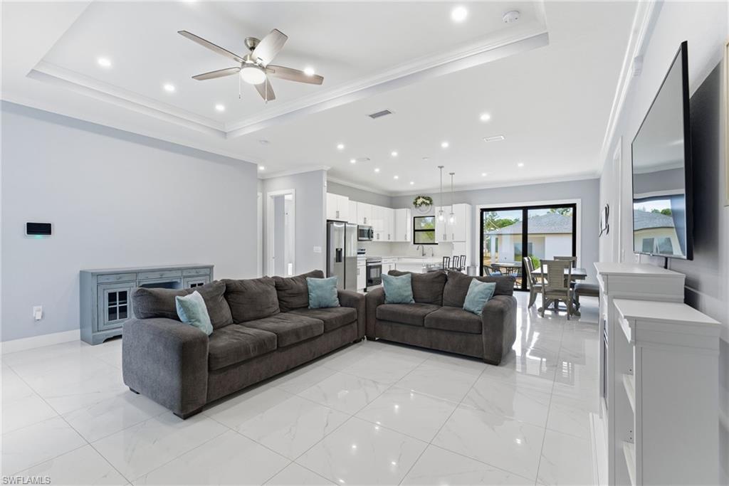 Living area featuring ceiling fan, ornamental molding, recessed lighting, and a raised ceiling