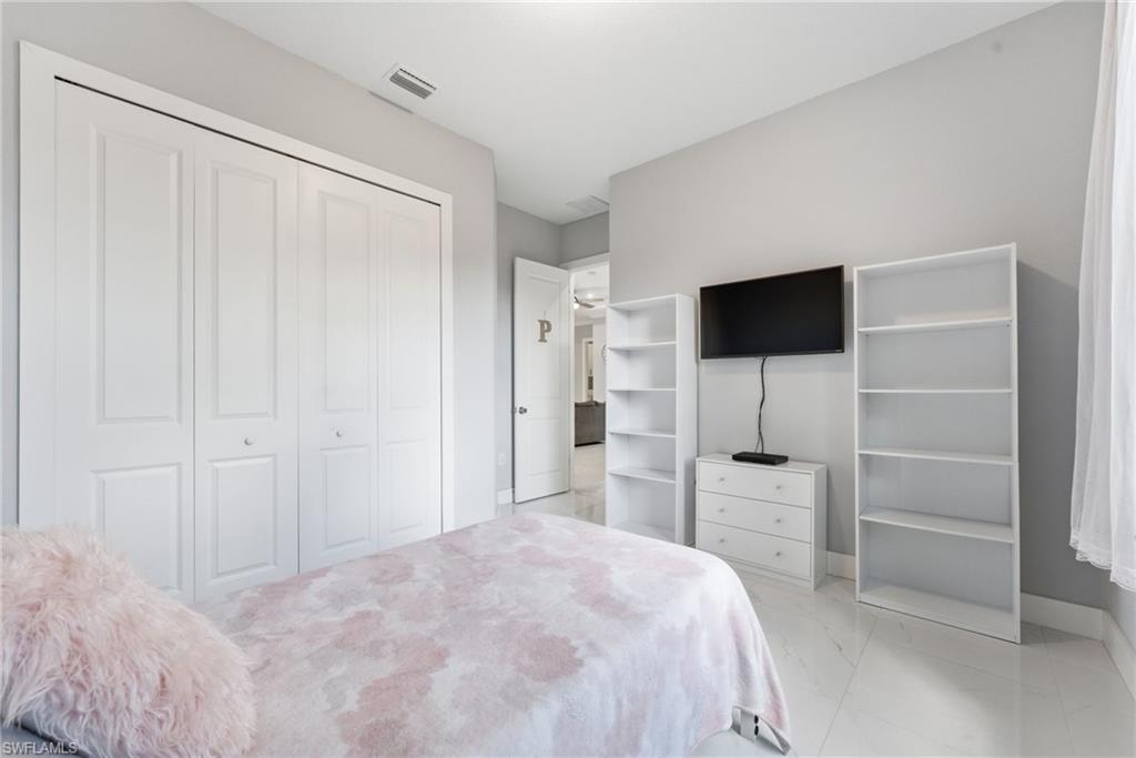 Bedroom featuring light marble finish flooring and a closet