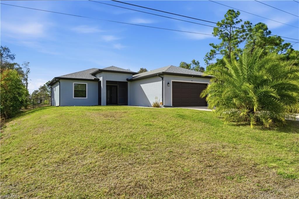 View of front of home with stucco siding, a front lawn, and an attached garage