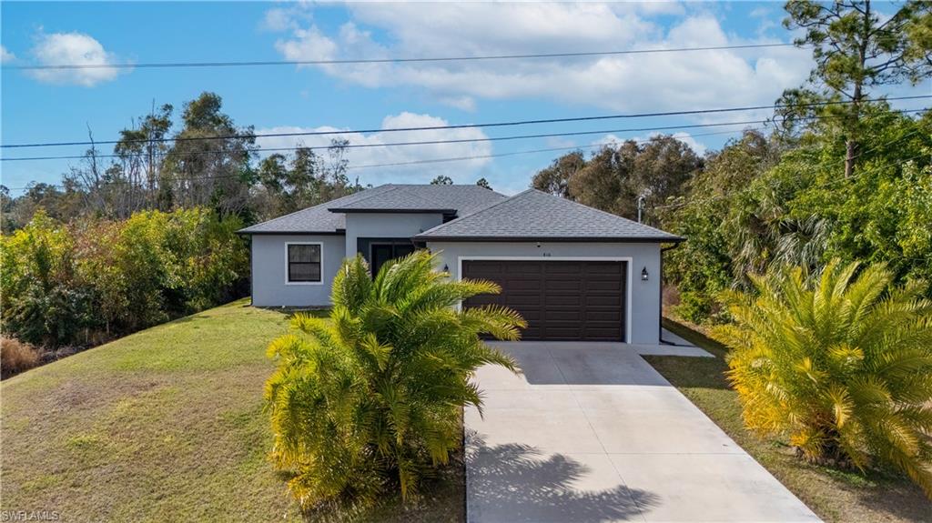 View of front of home featuring driveway, stucco siding, a front yard, and a garage