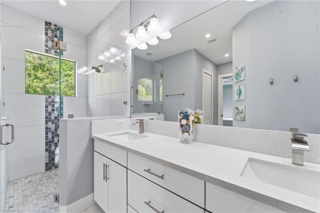 Full bathroom featuring a stall shower, double vanity, and recessed lighting