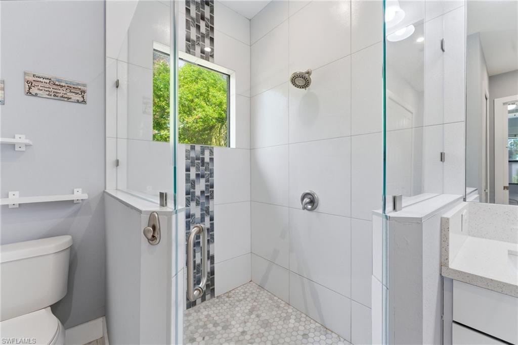 Bathroom featuring tiled shower and vanity