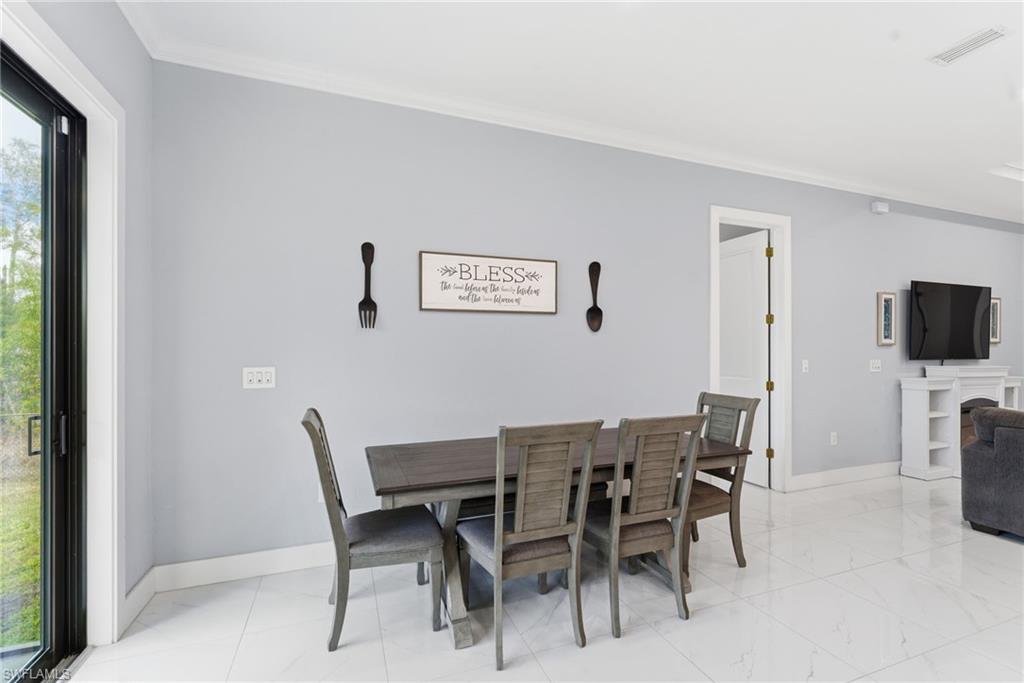 Dining space with crown molding and a fireplace