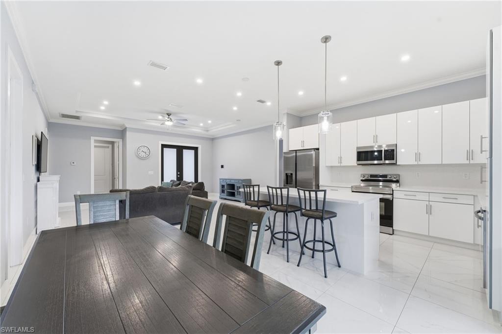 Dining area with crown molding, a ceiling fan, a tray ceiling, and recessed lighting