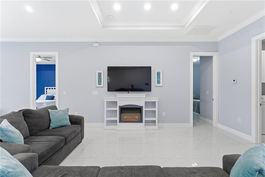 Living area with crown molding, a glass covered fireplace, and a raised ceiling