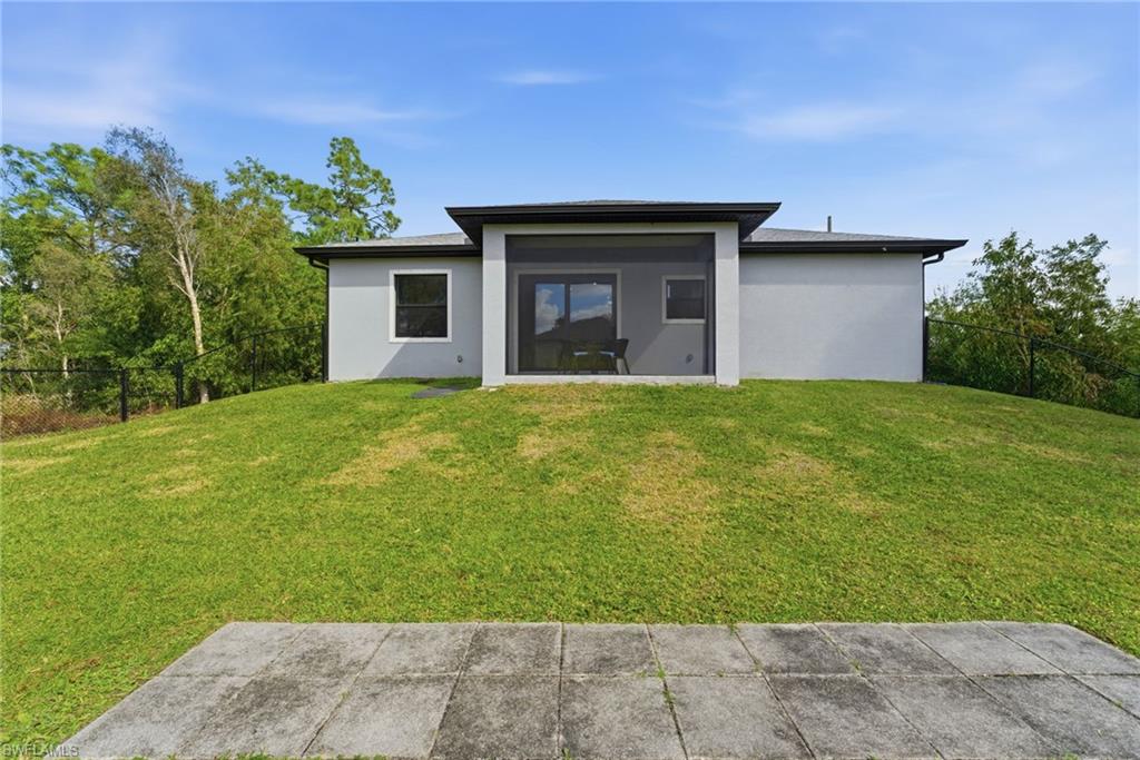 Back of house with a fenced backyard and stucco siding