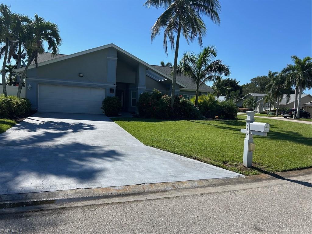 View of front of property with a front lawn, stucco siding, concrete driveway, and a garage