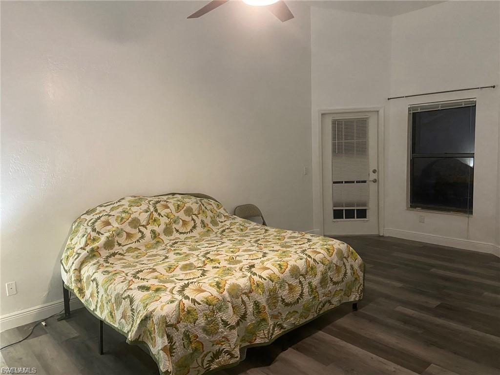 Bedroom with dark wood-style floors, ceiling fan, and a high ceiling