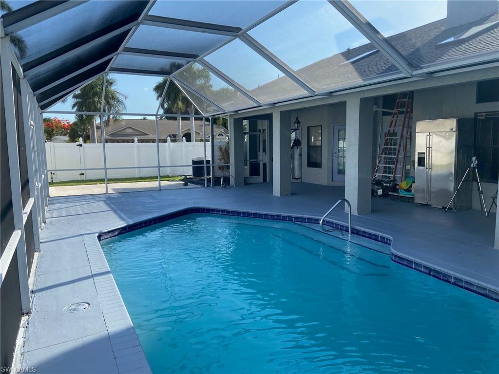 View of pool with a sunroom, patio surround, and glass enclosure