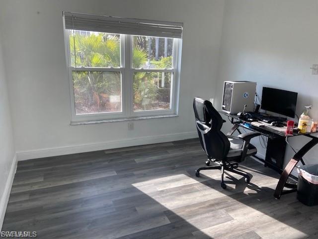 Home office with dark wood-style flooring and baseboards
