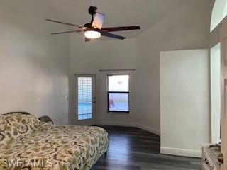 Bedroom with dark wood-style floors, a ceiling fan, and lofted ceiling