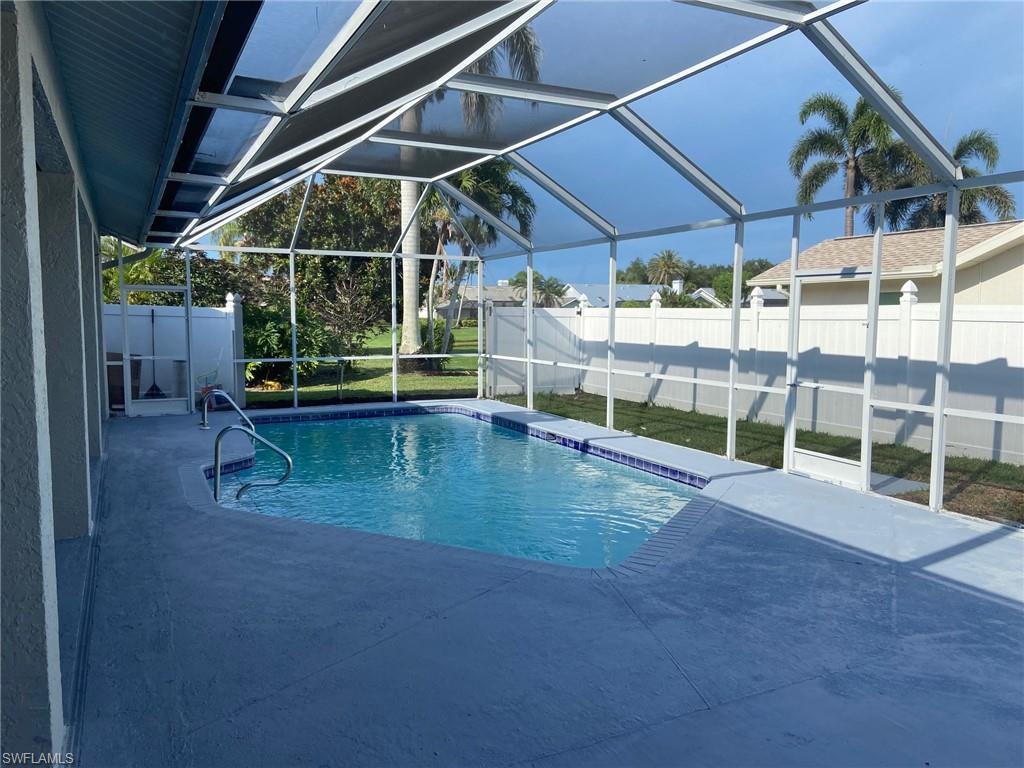 View of swimming pool with a fenced backyard, a sunroom, patio surround, and glass enclosure