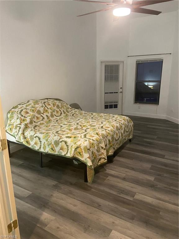 Bedroom with dark wood finished floors, ceiling fan, and a heating unit