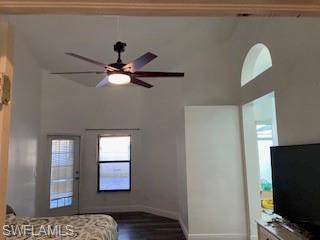 Bedroom featuring ceiling fan, dark wood-style floors, a high ceiling, and multiple windows