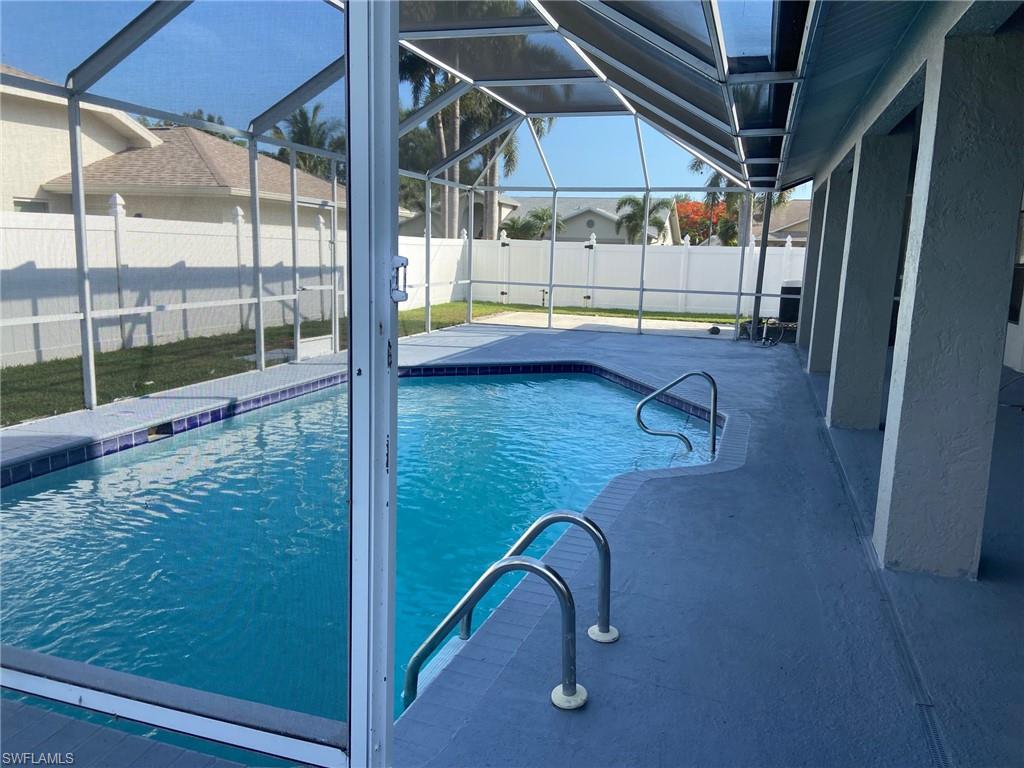 View of swimming pool with a sunroom, patio surround, glass enclosure, and a fenced backyard
