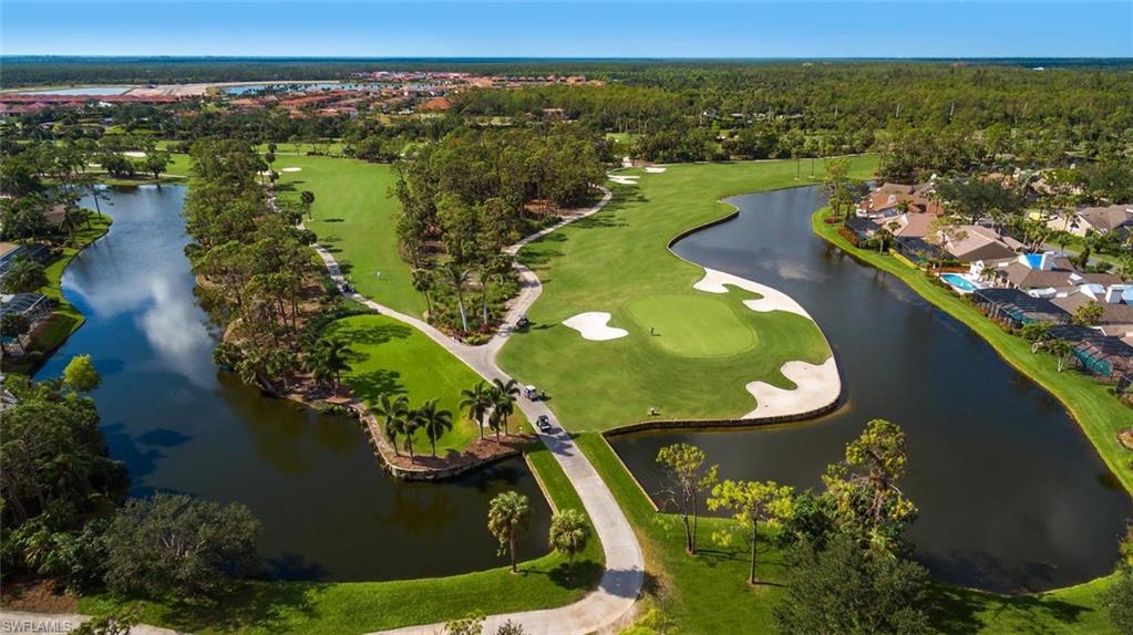 Aerial perspective of suburban area featuring a local golf course and a nearby body of water