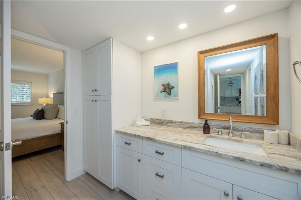 White shaker-style cabinetry with dark hardware, integrated vanity sink, and a large wood-framed mirror