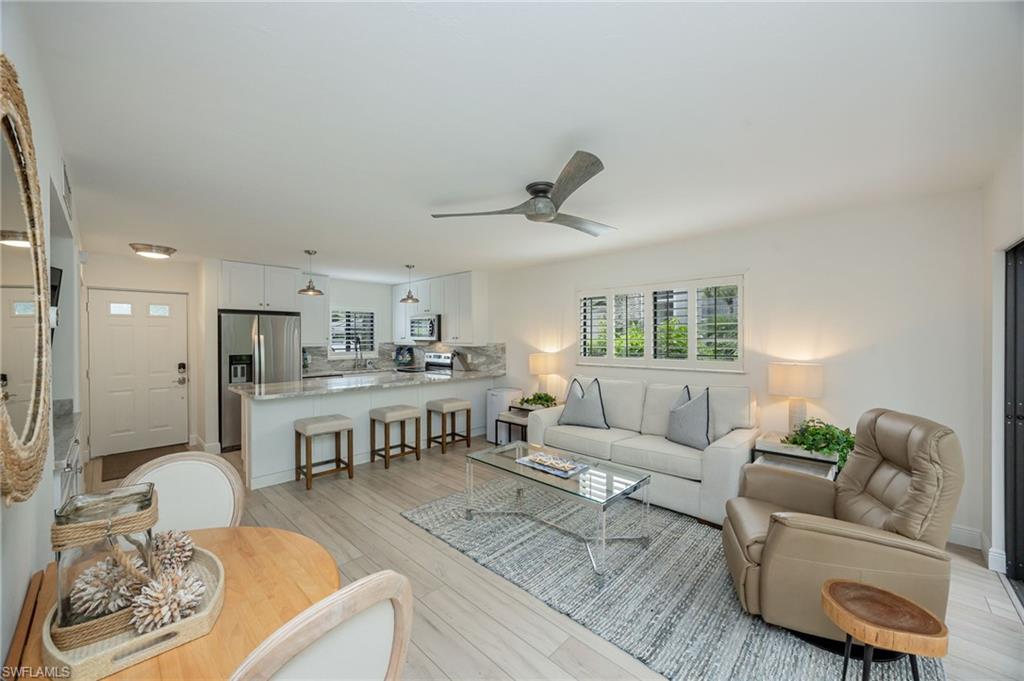 Open-concept living space featuring a modern kitchen, wood-finish flooring, and white cabinetry