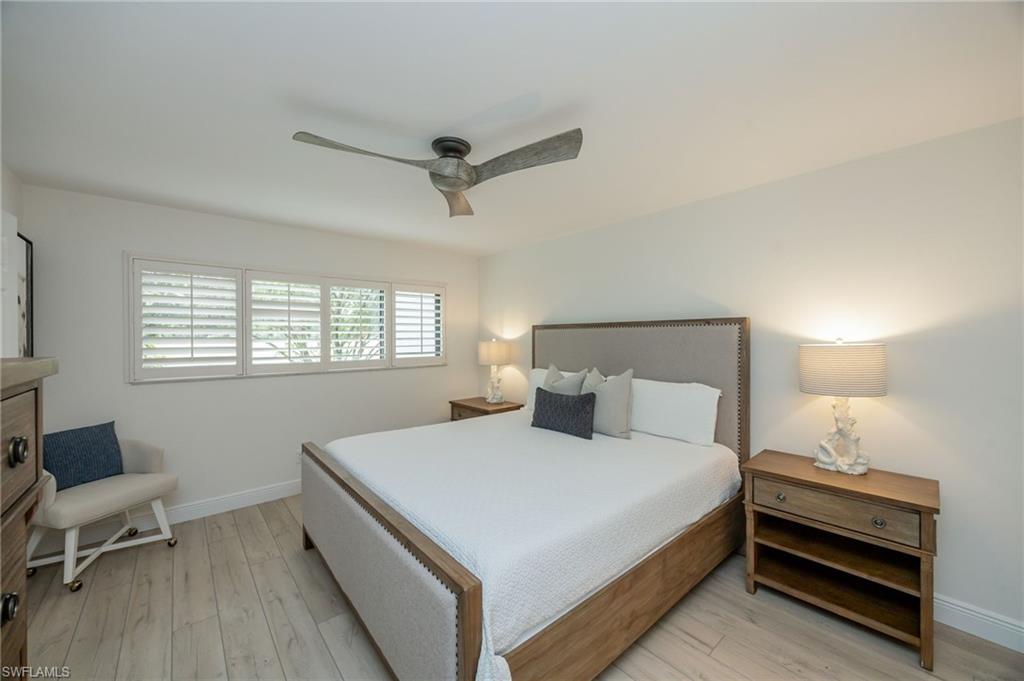 Wood-finish flooring, plantation shutters, and a ceiling fan with integrated lighting