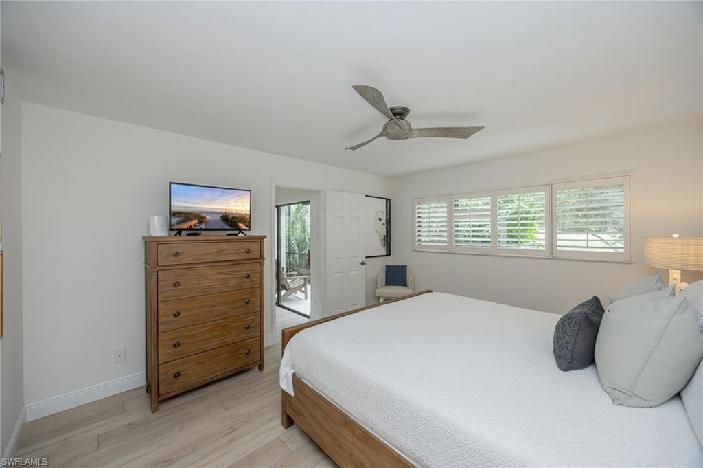 Wood-finish flooring, ceiling fan, white window shutters, and a glass-paneled door