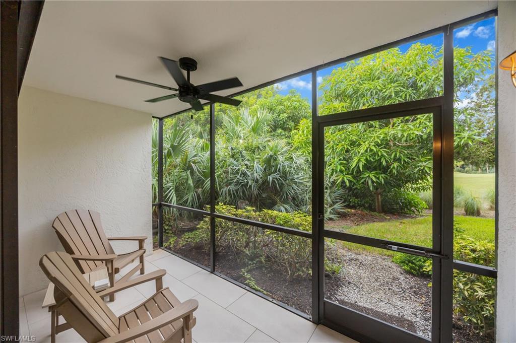 Screened outdoor area with light-toned tile flooring, a black ceiling fan, and a screened door leading to a landscaped exterior