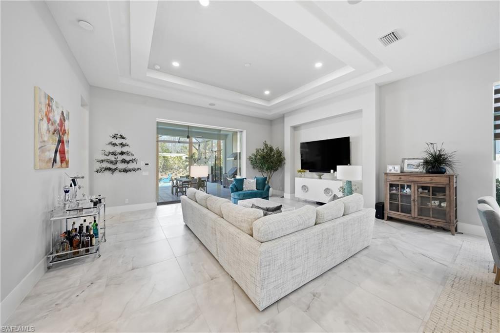 Expansive great room with tray ceiling detail and oversized sliders opening seamlessly to the lanai and pool area.