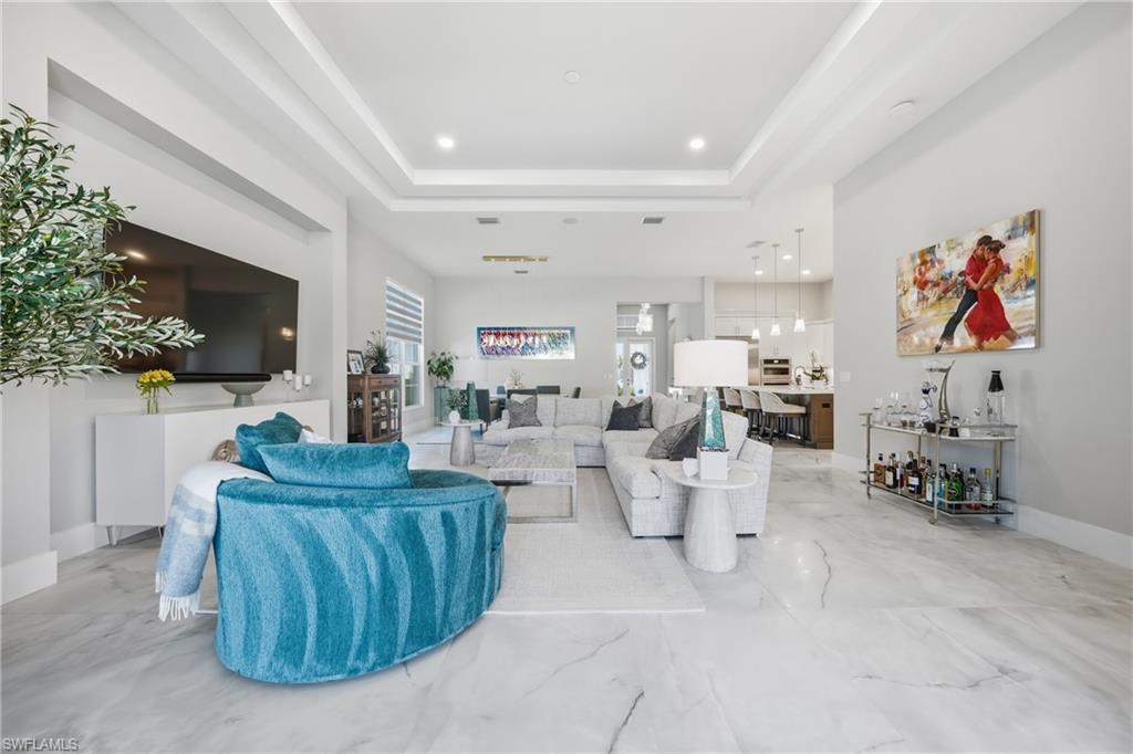 Expansive great room with tray ceiling detail and oversized sliders opening seamlessly to the lanai and pool area.