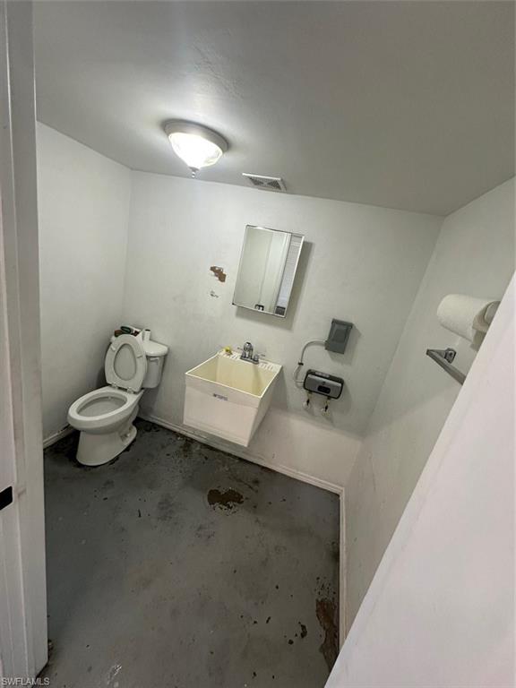 Half bathroom featuring toilet and unfinished concrete flooring