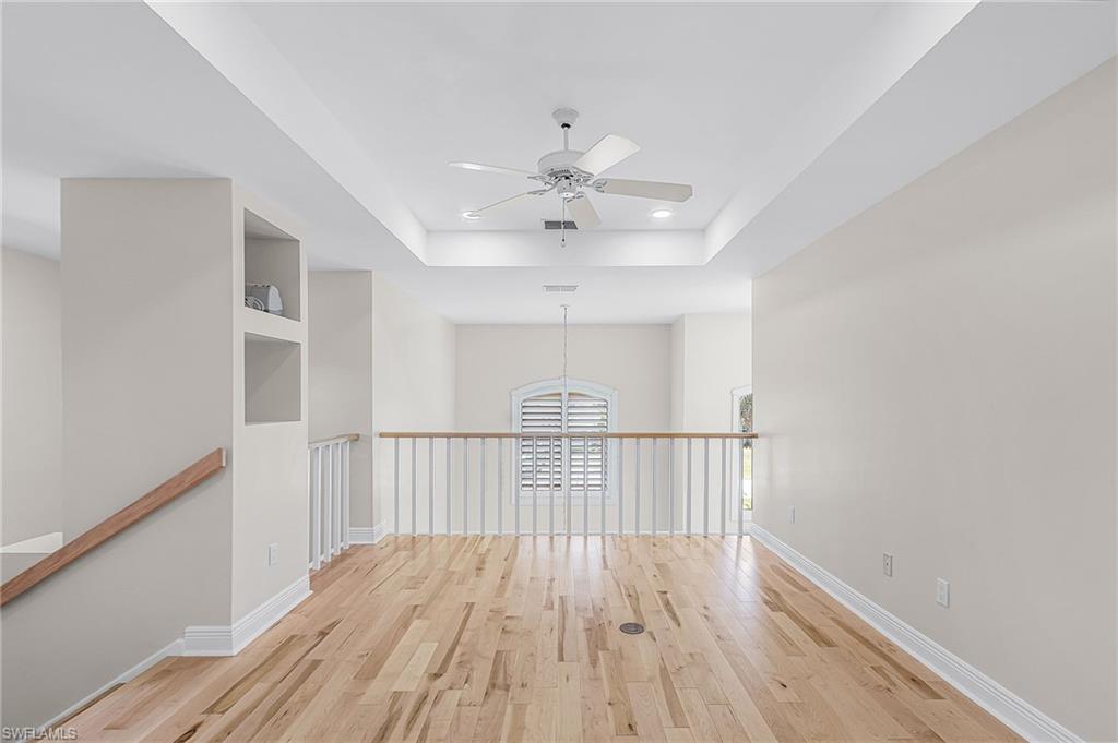 Loft featuring light wood-style flooring, a ceiling fan, a raised ceiling, and recessed lighting