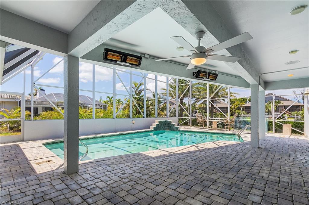 Swimming pool with glass enclosure, a patio area, and a sunroom
