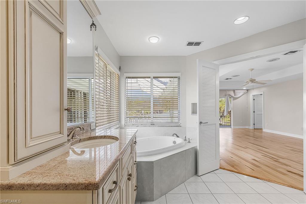 Primary Bathroom featuring light tile patterned flooring, vanity, a garden tub, ceiling fan, and recessed lighting