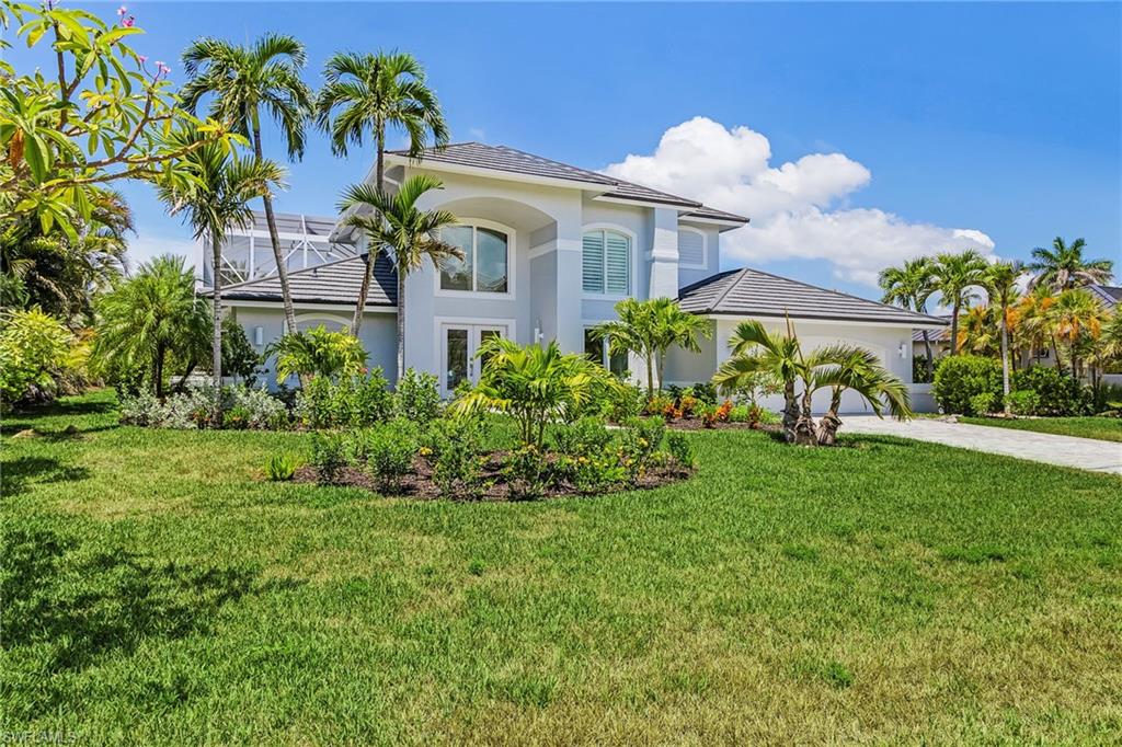 View of front of property featuring a front yard, stucco siding, driveway, and an attached garage