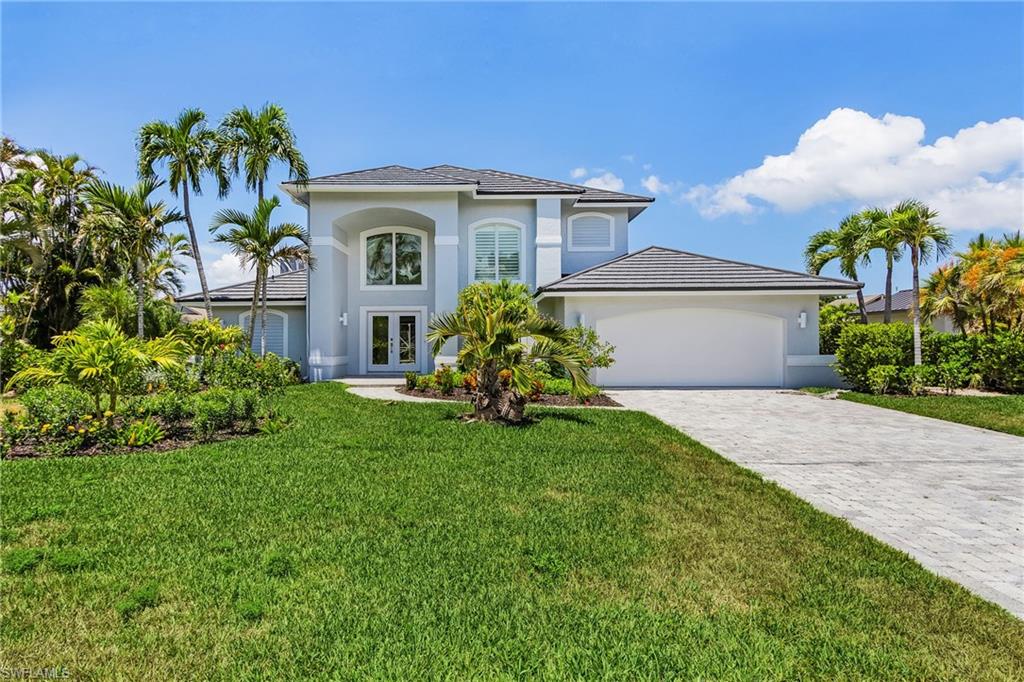 View of front of home with french doors, stucco siding, a front yard, decorative driveway, and an attached garage