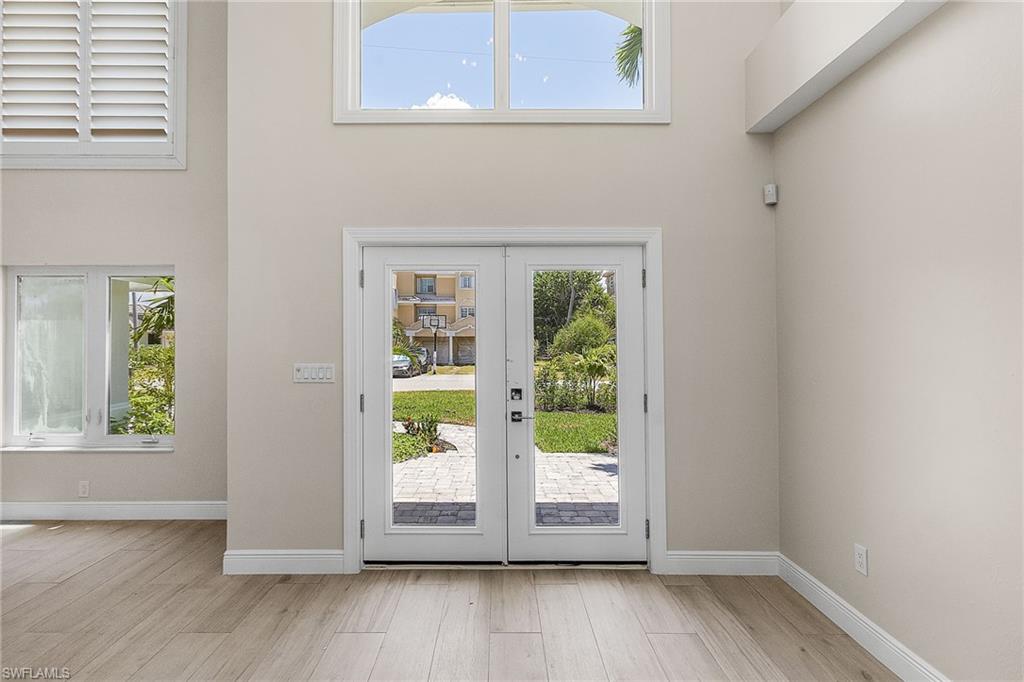 Doorway to outside with french doors, wood finished floors, and a high ceiling