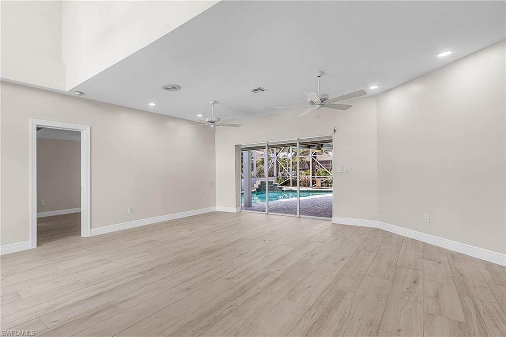 Family room featuring light wood finished floors, recessed lighting, a ceiling fan, and a high ceiling