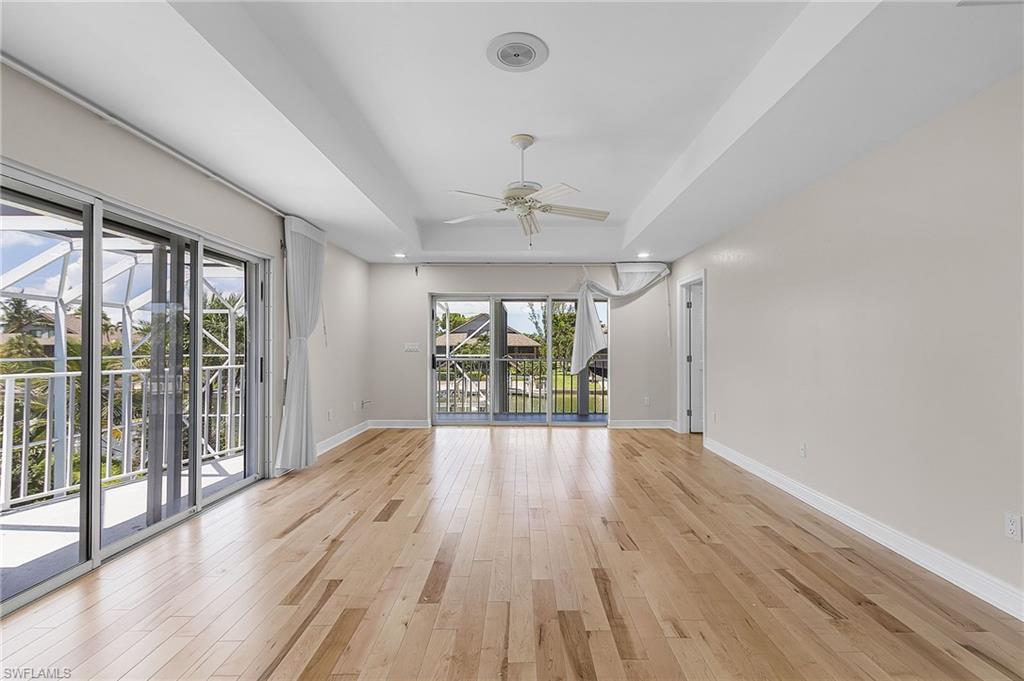 Primary Bedroom with a tray ceiling, a ceiling fan, light wood-type flooring, and recessed lighting