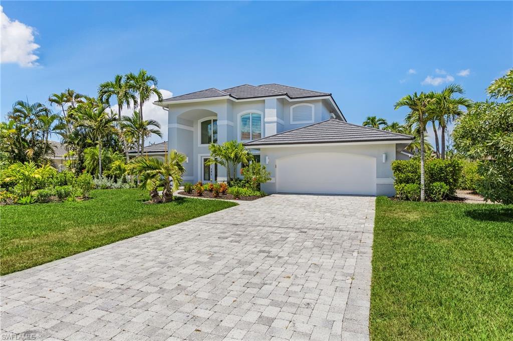 View of front of home with a front lawn, decorative driveway, an attached garage, and stucco siding